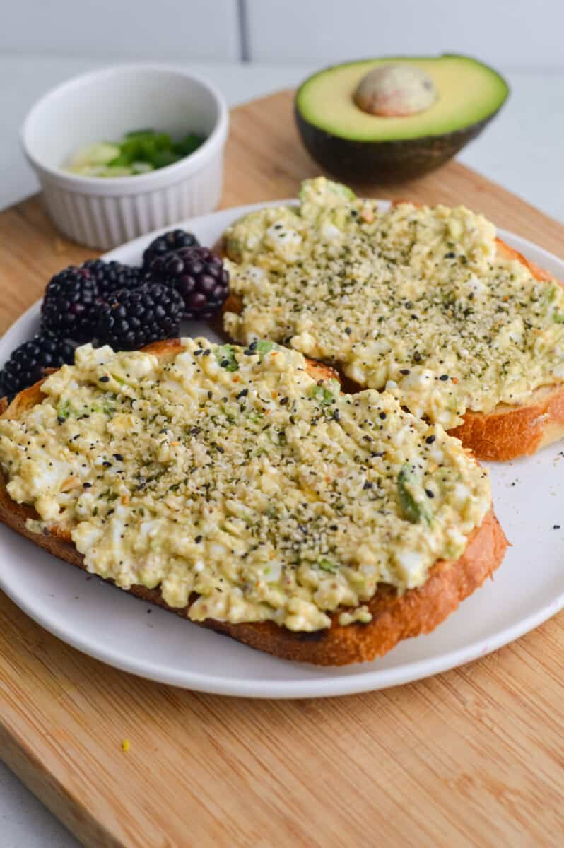 Two slices of avocado cottage cheese toast served with blackberries.