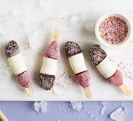 4 frozen banana lollies decorated with chocolate, hundreds and thousands and strawberries