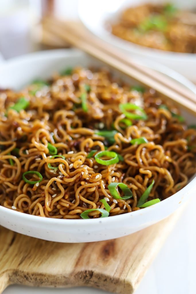 garlic chili oil noodles with green onions in white speckled bowl.