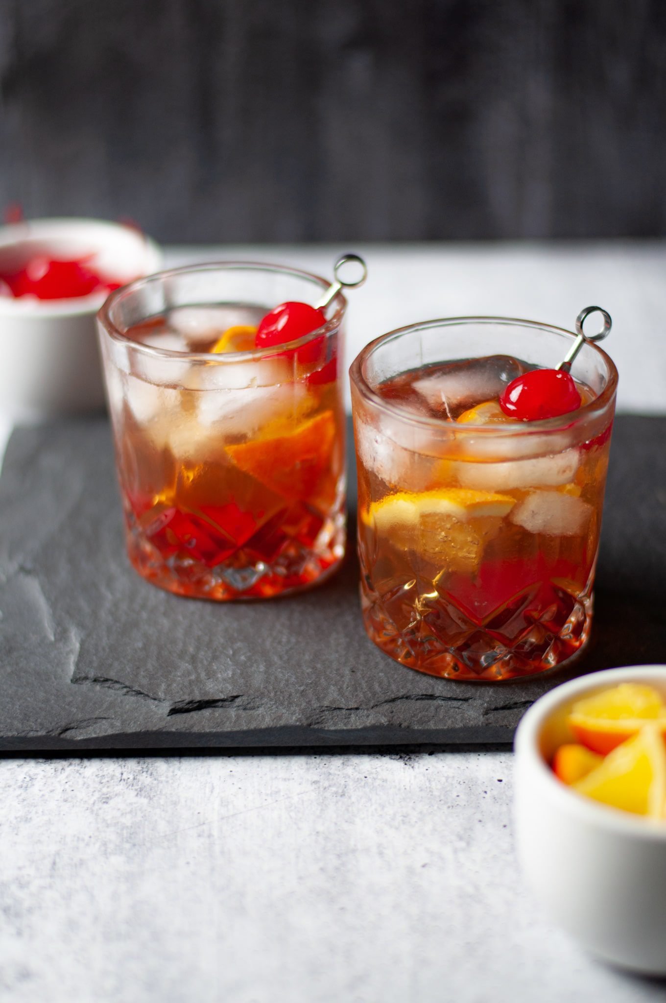 Two rocks glasses filled with this classic Wisconsin Brandy Old Fashioned Recipe and garnished with orange slices and a cherry