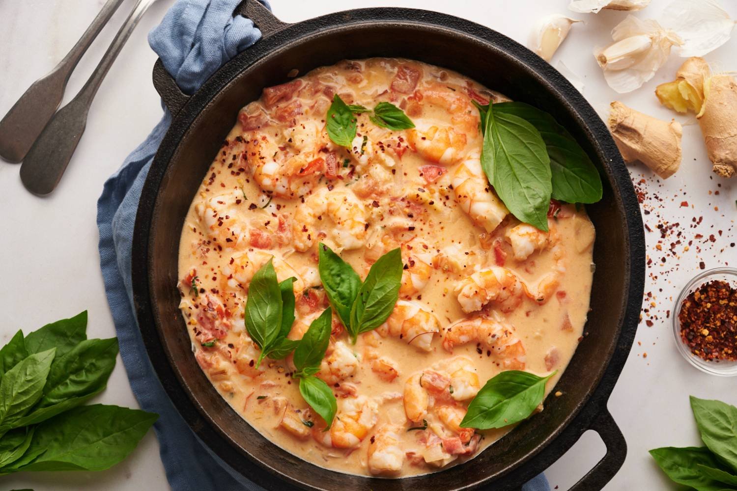 Creamy Coconut Shrimp with Tomatoes Creamy coconut shrimp with tomatoes, coconut milk, basil, and red pepper flakes in a black skillet.