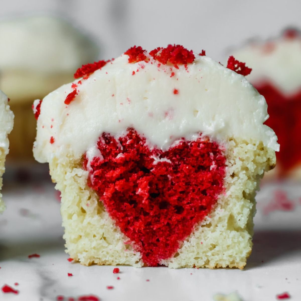 A cupcake sliced in half with a red heart baked inside.