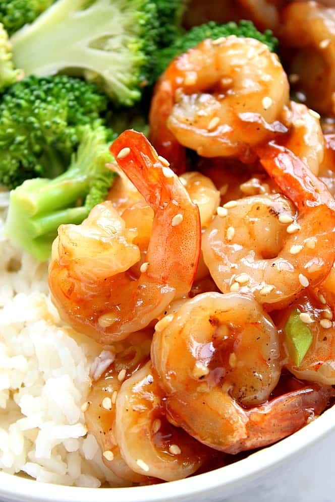 Close up on teriyaki shrimp with tails next to rice and broccoli. 