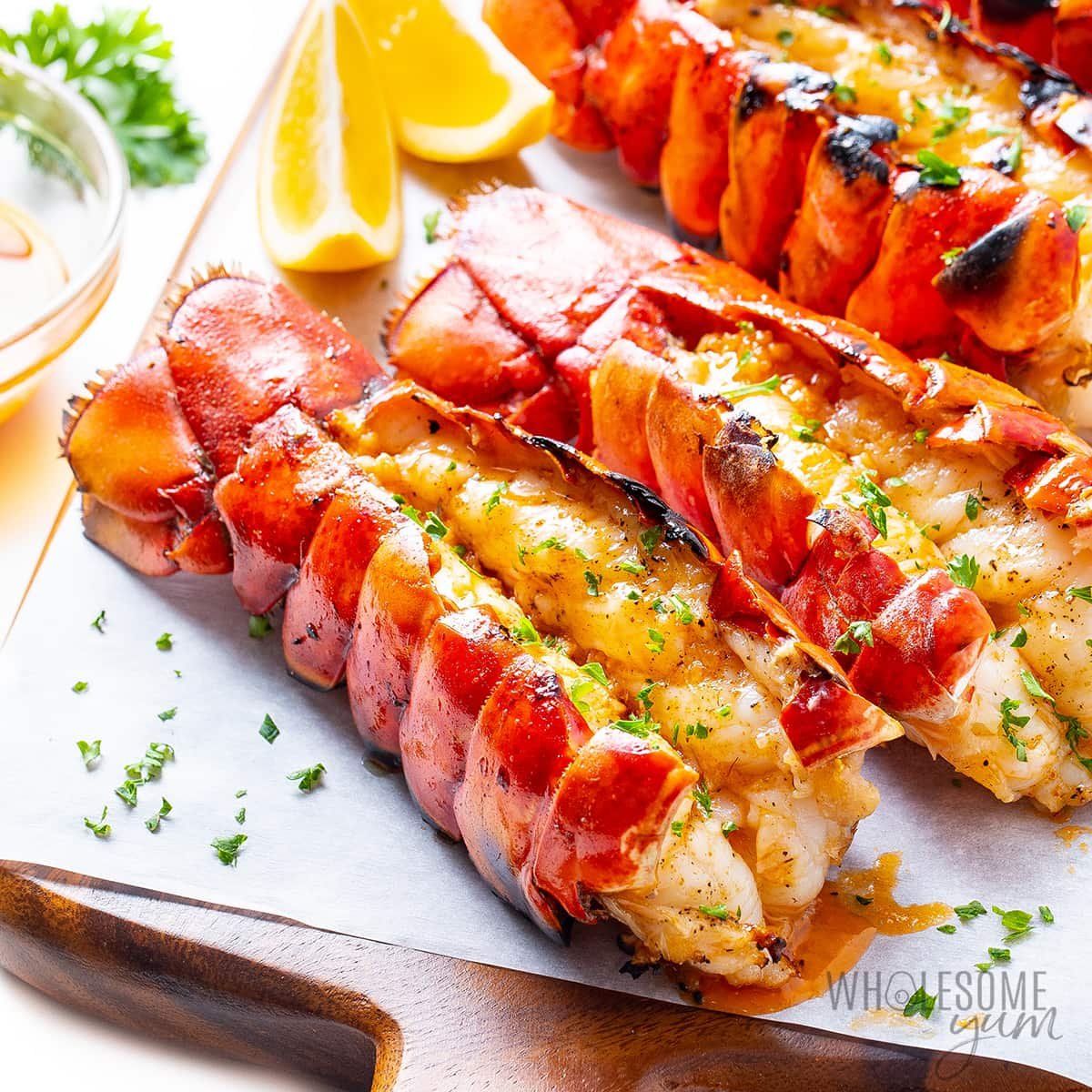 Grilled lobster tail on a cutting board.