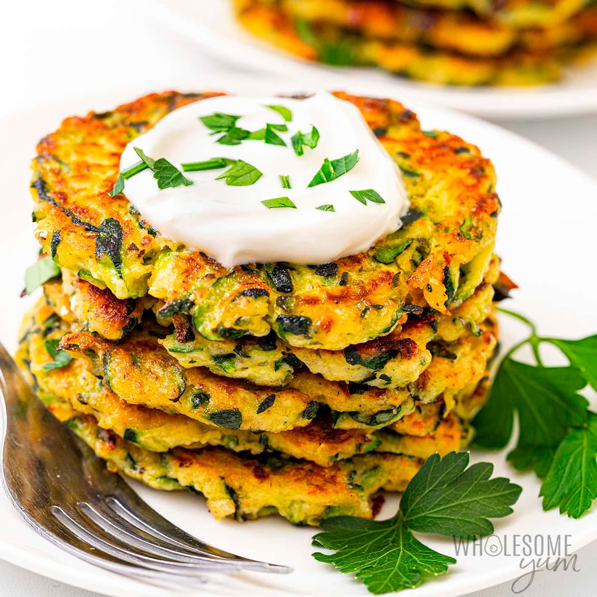 Zucchini fritters stacked on a plate.