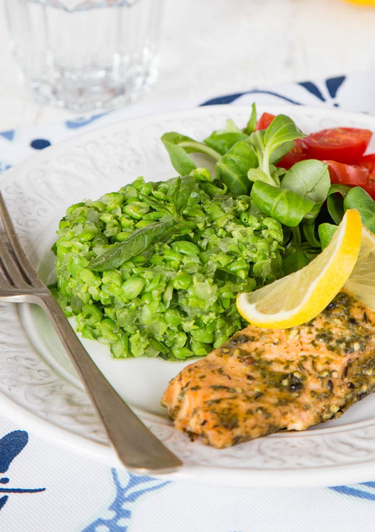 Deliciously vibrant green crushed minted peas, served on a white plate with some hot smoked salmon.