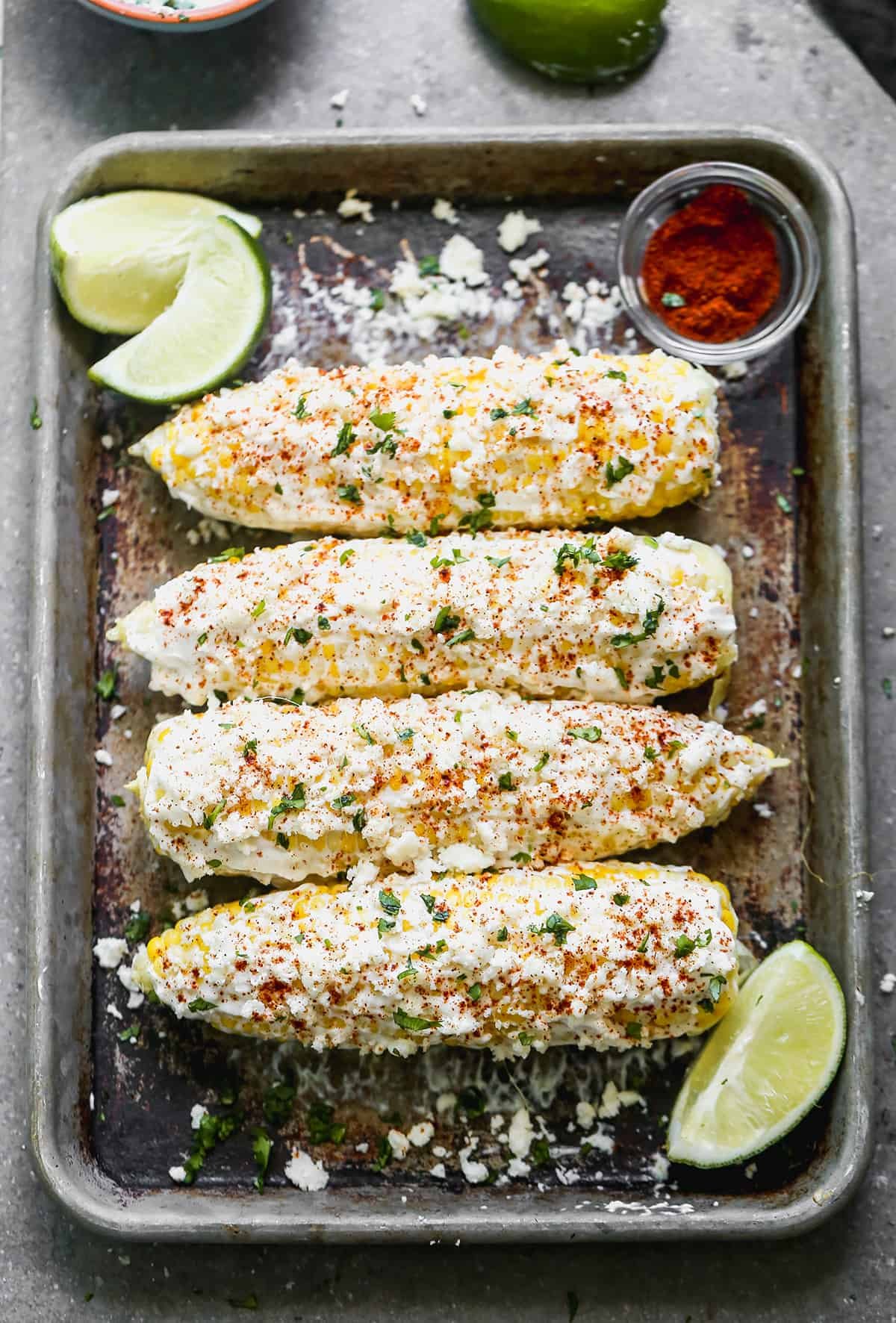 A baking sheet with four cobs of Elote ready to enjoy.