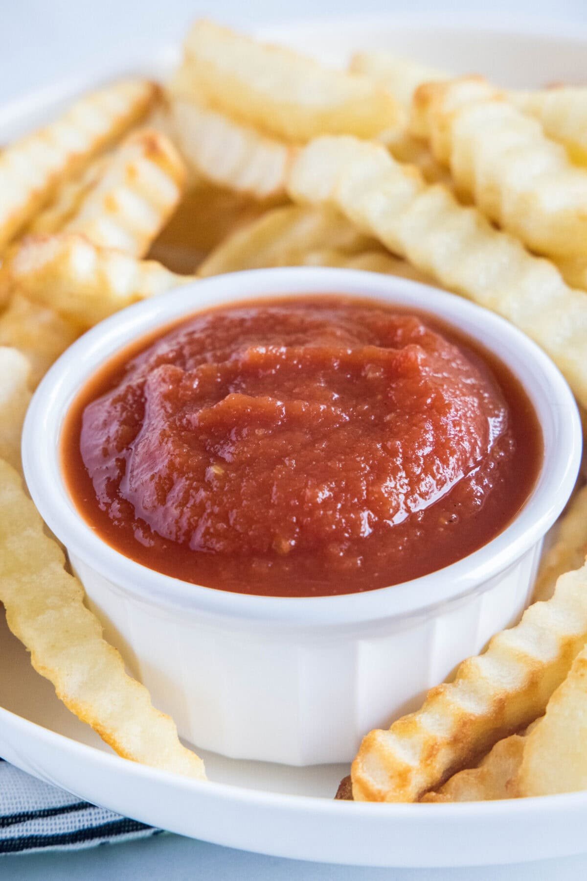 Homemade ketchup is tangy, salty, smooth, and so much better than the store-bought kind. Plus, it's easy to make and takes less than an hour. A ramekin of ketchup on a plate of fries