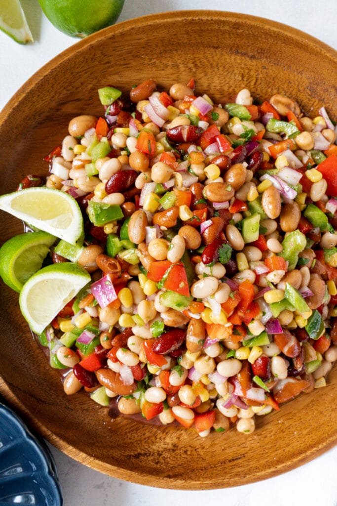 A large bowl of 4-bean salad and lime wedges