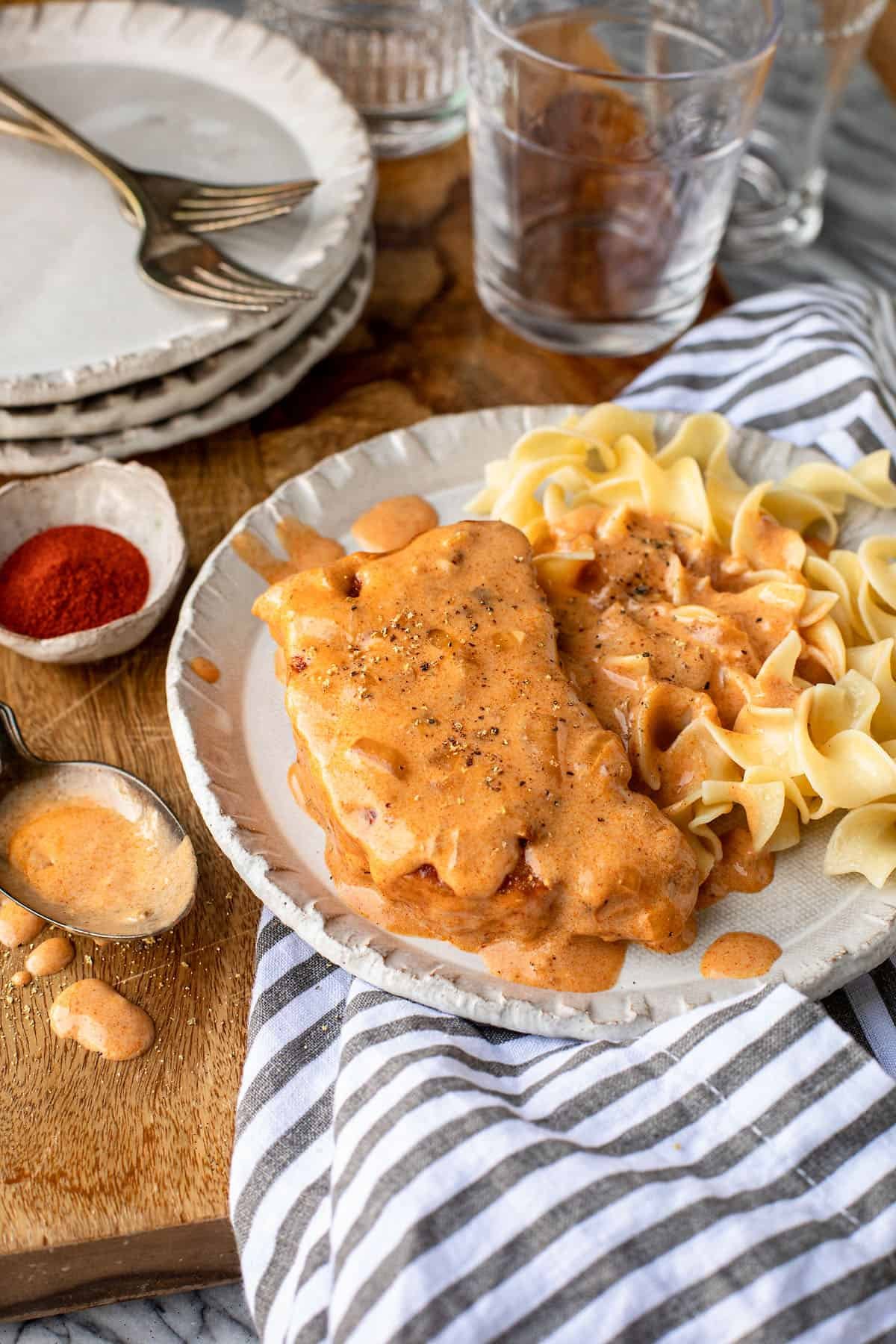 sour cream pork chops served over eggs noodles with a stripe napkin
