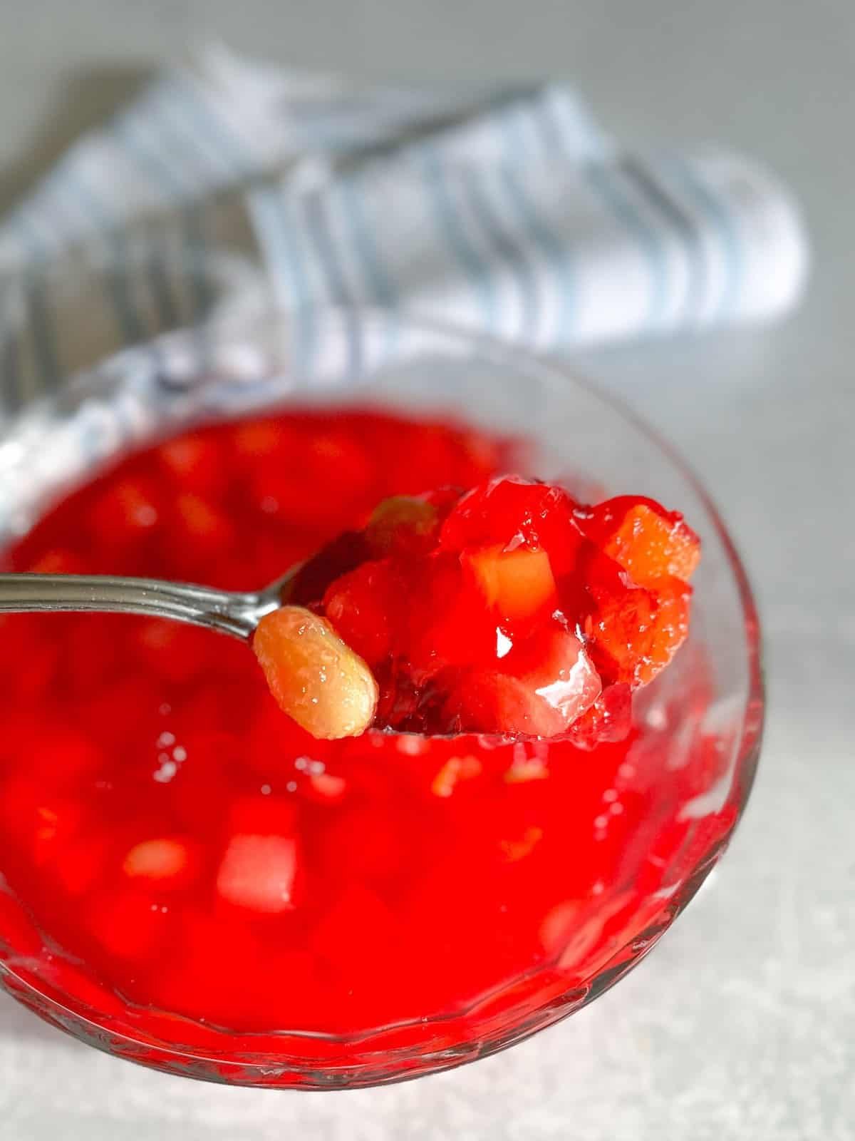 Jello and fruit cocktail on a serving spoon.
